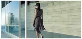 Person im Kleid geht an einer modernen Glasfassade entlang