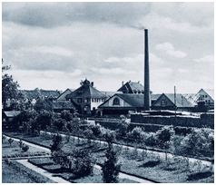 Schwarz-weiß-Aufnahme eines Industrieareals mit Schornstein