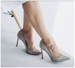 Detailaufnahme von Schuhen mit hohen Absätzen an den Füßen einer Person