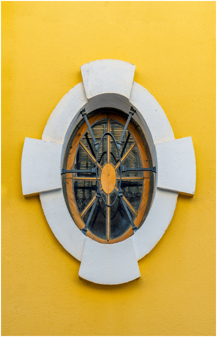 Ovales Fenster mit Holz- und Metallrahmen in einer Hausfassade