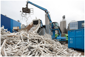 Recyclinganlage mit Förderband, Kran und gestapelten Kunststofffensterrahmen
